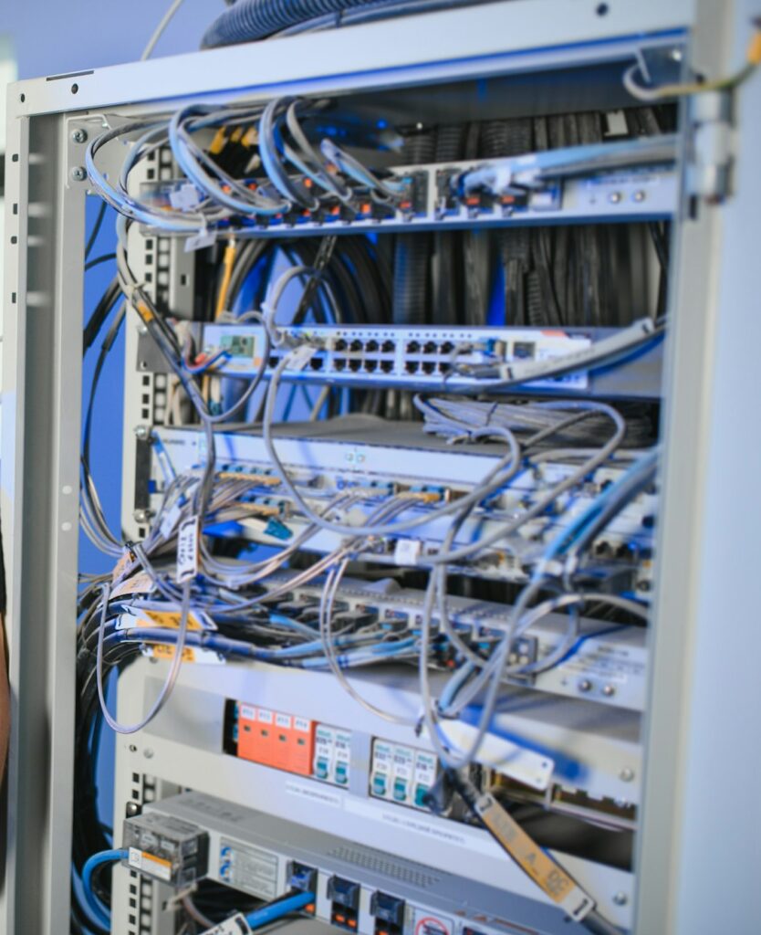 A technician works with server equipment in a data center. A man commutes wires in a server room