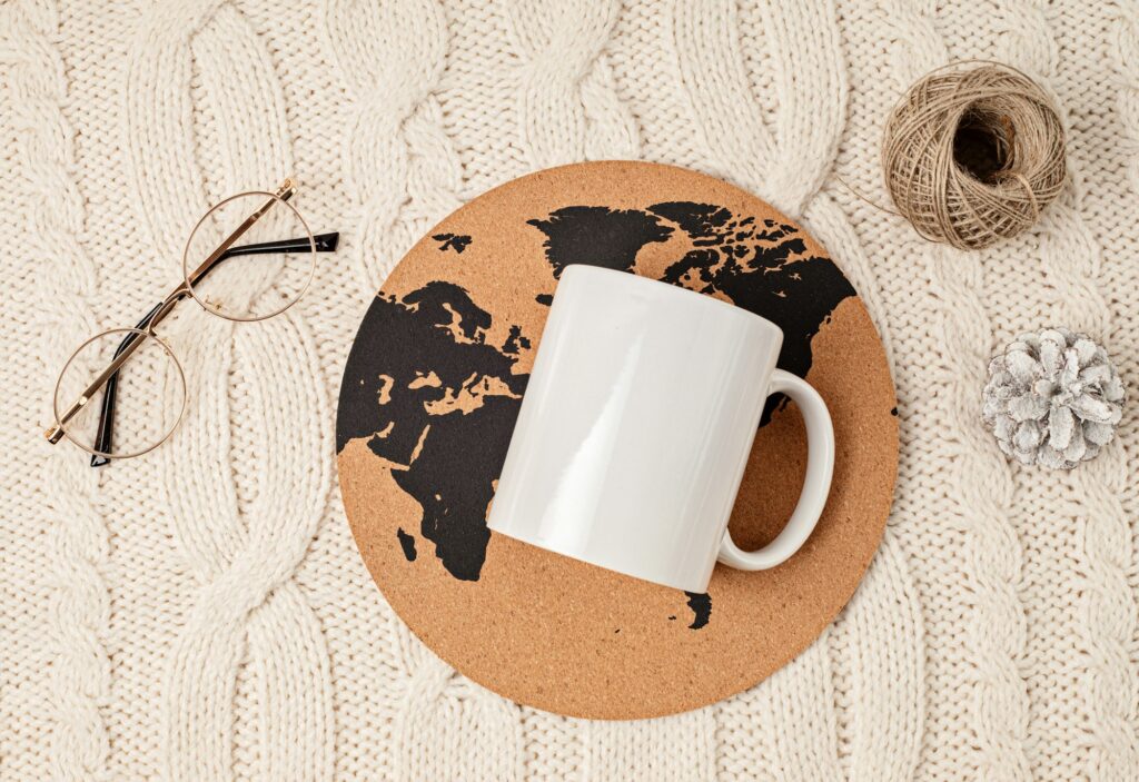 Mockup with white mug, glasses, watch, pen, notebook and globe print